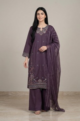 Woman wearing a purple embroidered traditional outfit with a plain background