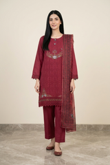 Woman wearing a maroon traditional outfit with embroidery on a beige background