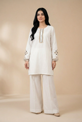 Woman wearing a white embroidered outfit on a beige background