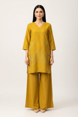 Woman wearing a mustard yellow outfit with a plain background