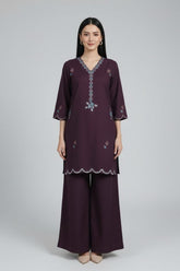 Woman wearing a dark purple embroidered outfit on a white background