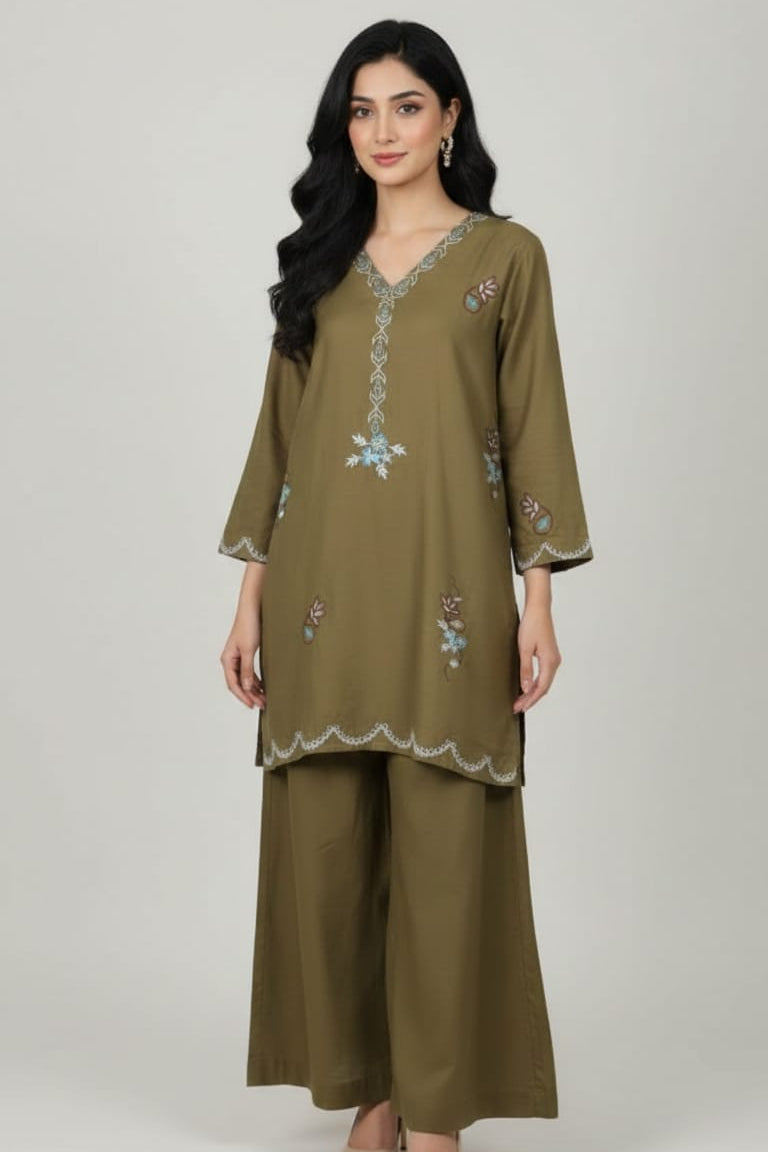 Woman wearing an olive green embroidered outfit on a white background