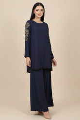 Woman wearing a navy blue outfit with gold embroidery on a beige background