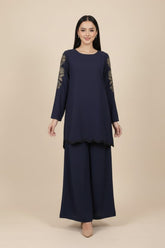 Woman wearing a navy blue outfit with Embroidered sleeves on a beige background