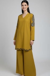 Woman wearing a mustard yellow outfit with black details on a white background