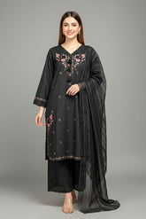Woman wearing a black embroidered outfit with a sheer dupatta on a gray background