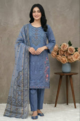 Woman wearing a blue embroidered outfit with a matching dupatta, standing next to a vase of flowers on a wooden table.