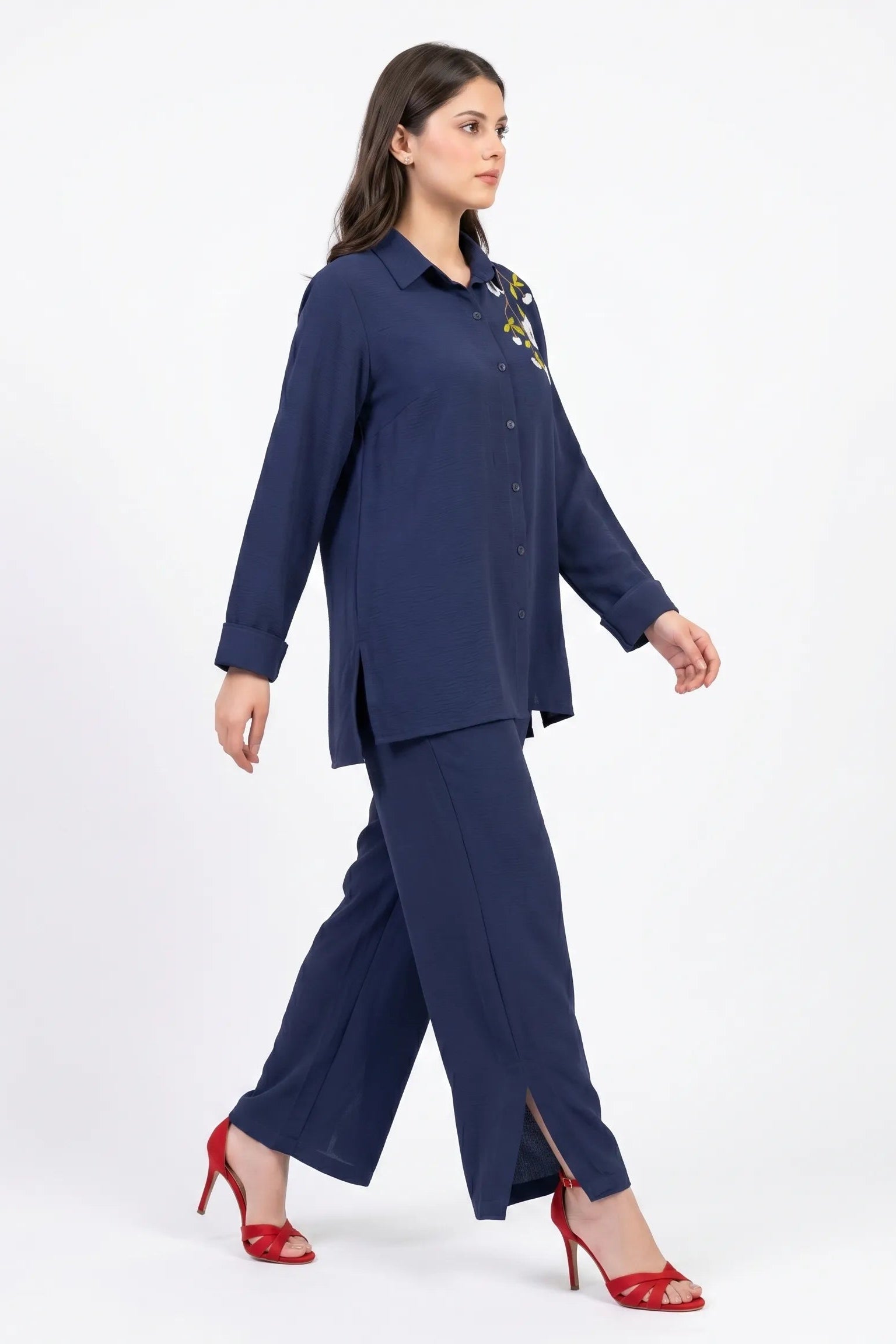 Woman wearing a navy blue outfit with red shoes on a white background