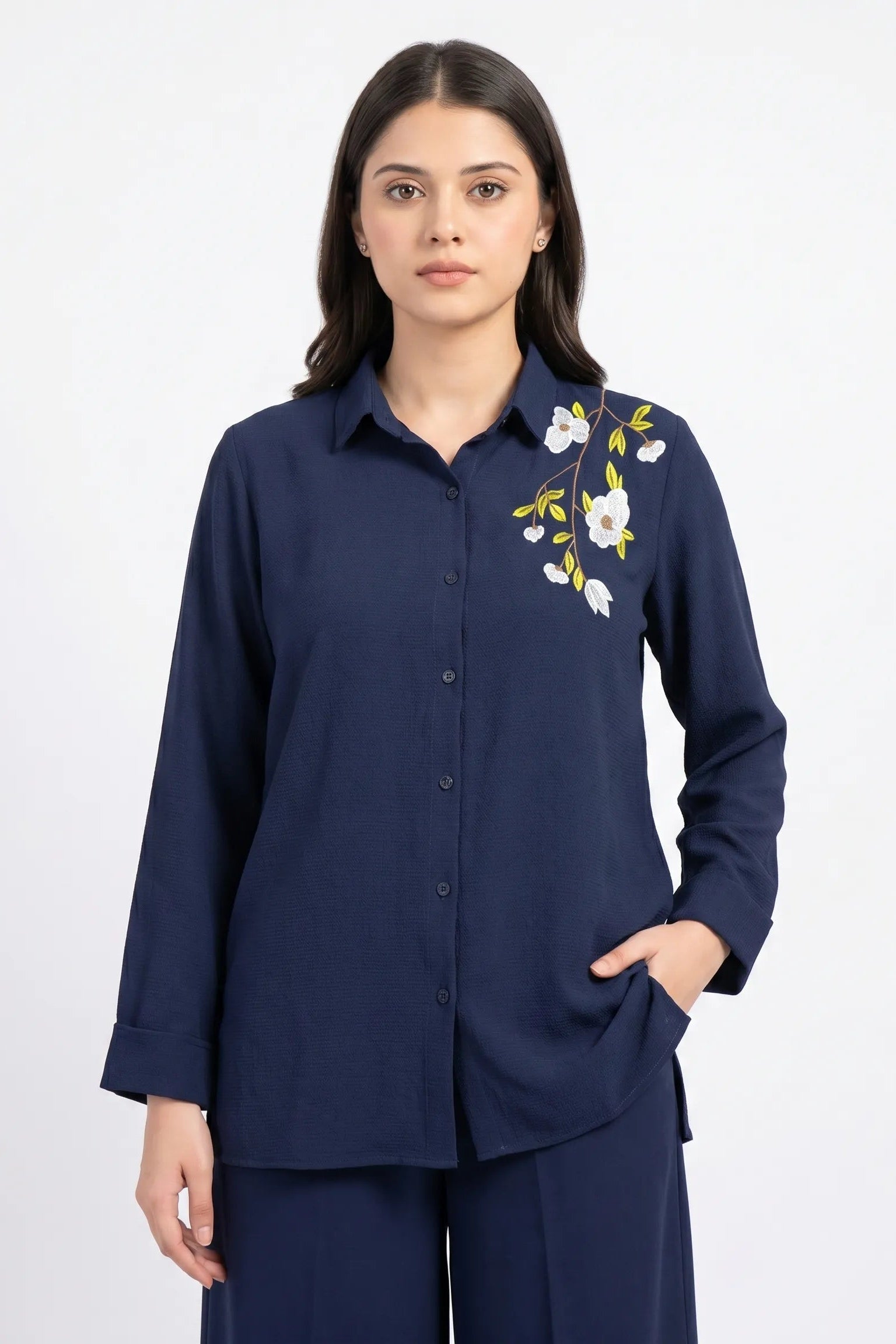 Woman wearing a navy blue shirt with floral embroidery on a white background