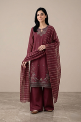 Woman wearing a maroon traditional outfit with embroidery against a beige background