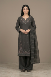 Woman wearing a dark gray traditional outfit with intricate embroidery on a plain background