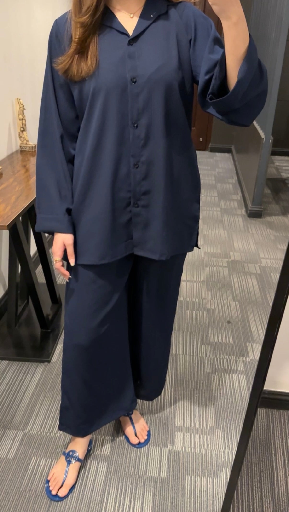 Person wearing a navy blue outfit standing in an indoor setting.