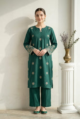 Woman wearing a green traditional outfit with a white wall and decorative elements in the background