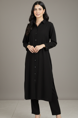 Woman wearing a black long shirt and pants against a neutral background