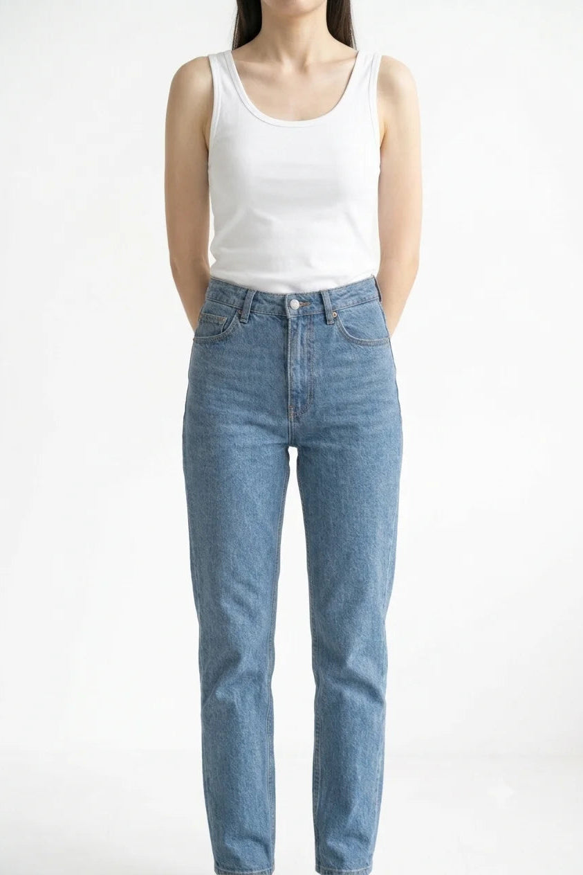 Front view of white premium women's cotton tank top tucked into blue jeans