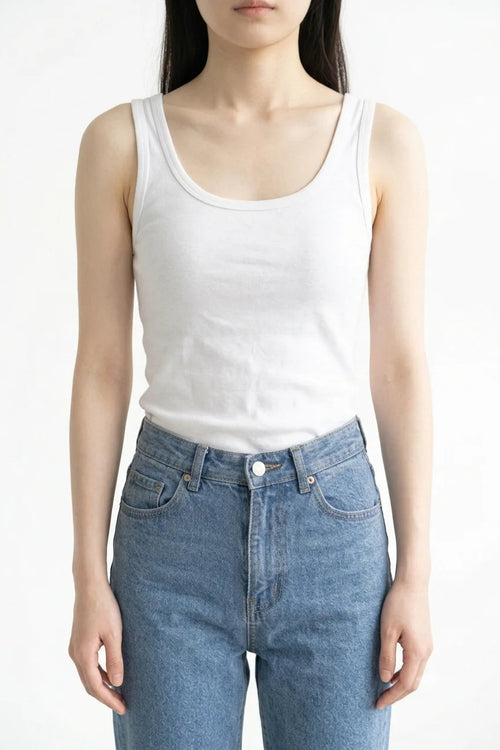 Front view of white premium women's cotton tank top tucked into blue jeans
