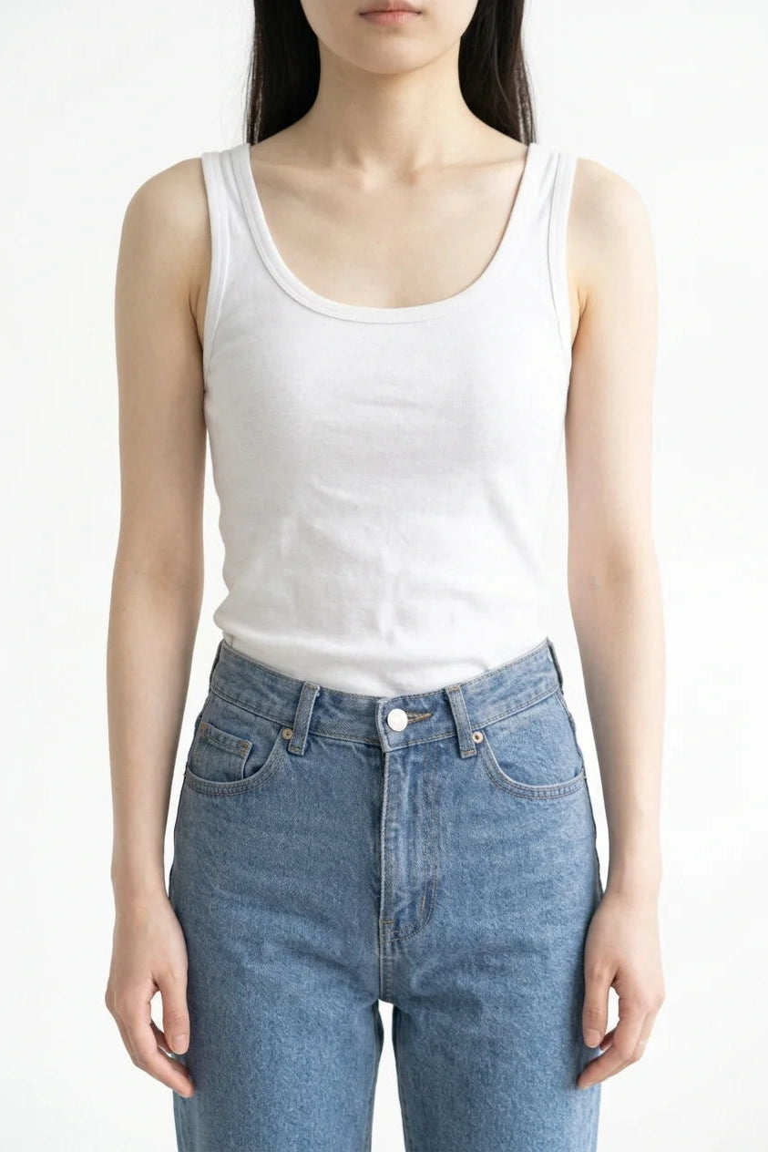 Front view of white premium women's cotton tank top tucked into blue jeans