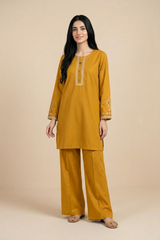 Woman wearing a mustard yellow kurta with embroidery on a beige background