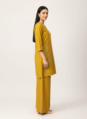 Woman wearing a mustard yellow outfit on a white background