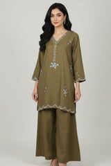 Woman wearing an olive green embroidered outfit on a white background