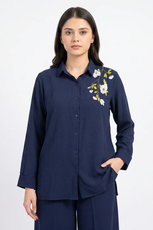 Woman wearing a navy blue shirt with floral embroidery on a white background