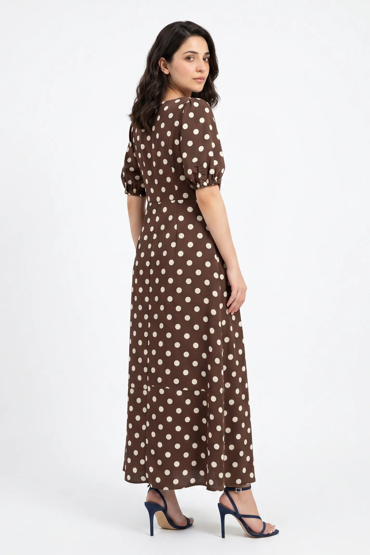 Woman wearing a brown dress with white polka dots on a white background