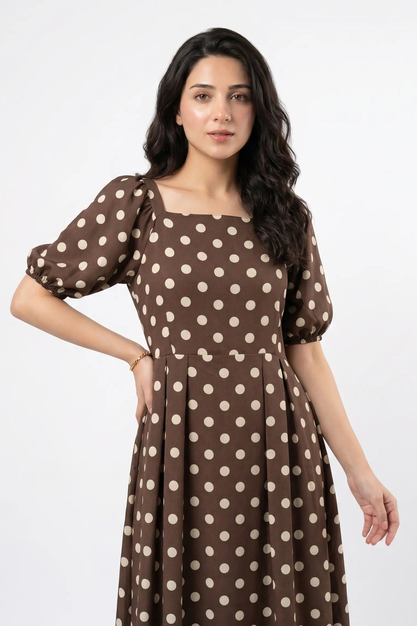 Woman wearing a brown dress with white polka dots on a white background