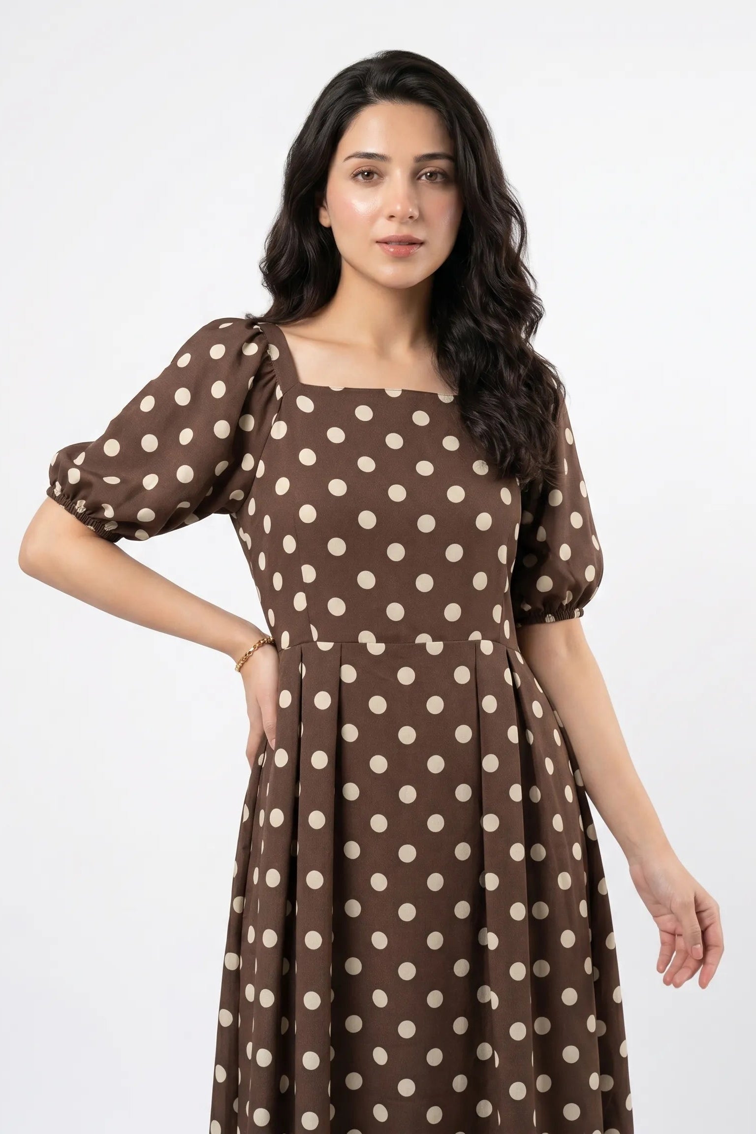 Woman wearing a brown dress with white polka dots on a white background