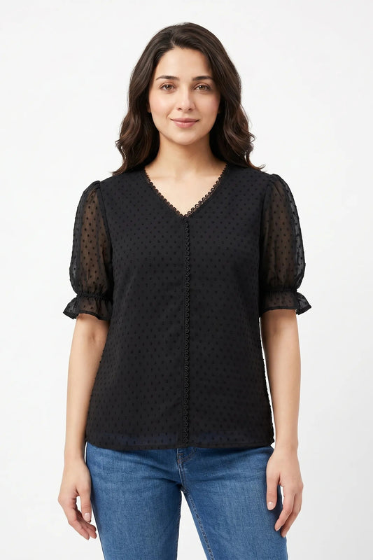 Woman wearing a black patterned blouse with sheer sleeves on a white background