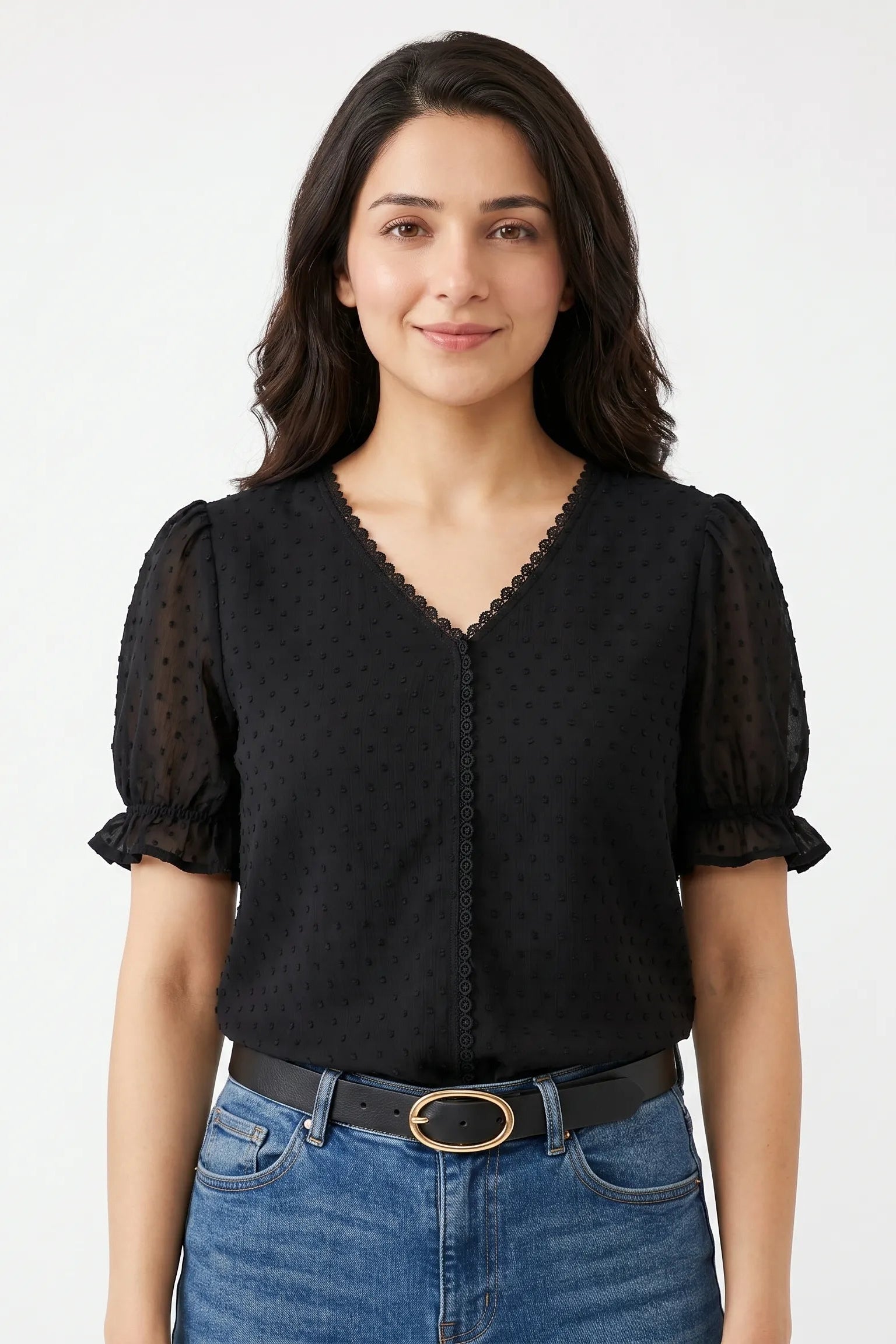 Woman wearing a black blouse with sheer sleeves and blue jeans on a white background