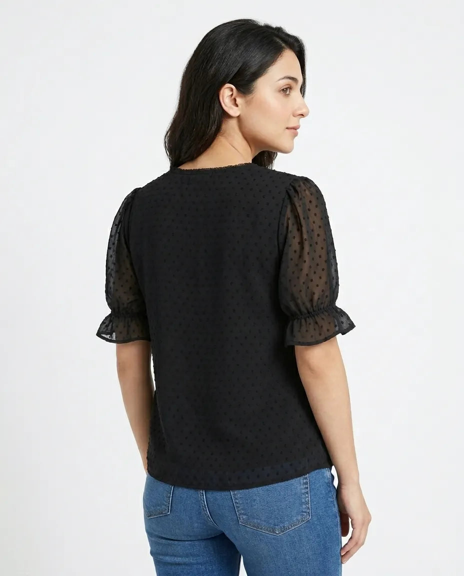 Woman wearing a black top with sheer sleeves on a white background