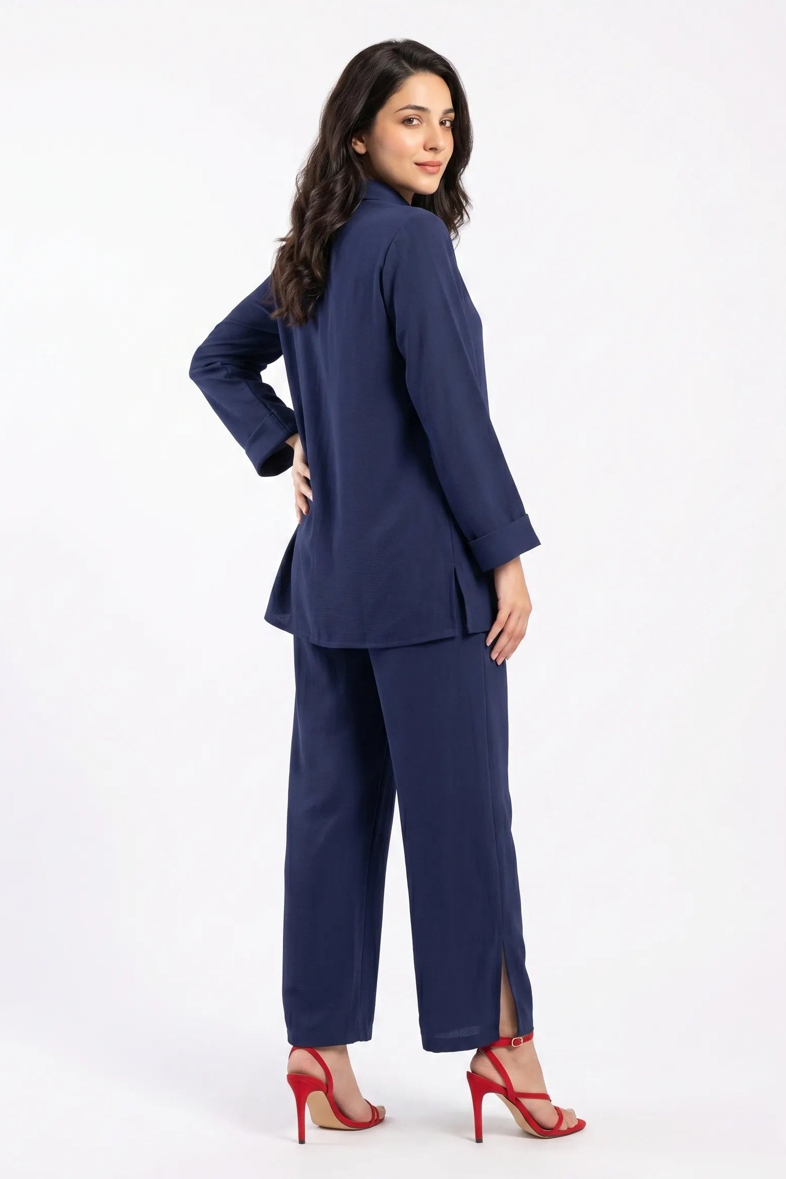 Woman wearing a navy blue suit with red high heels on a white background