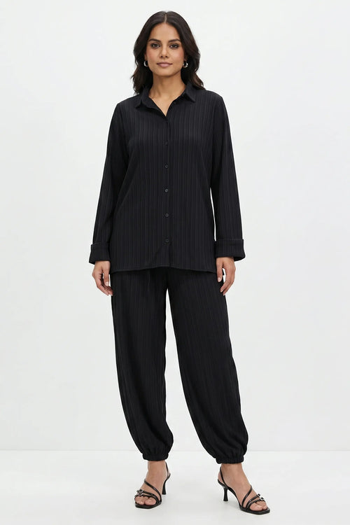 Woman wearing a black pinstripe shirt and pants on a white background