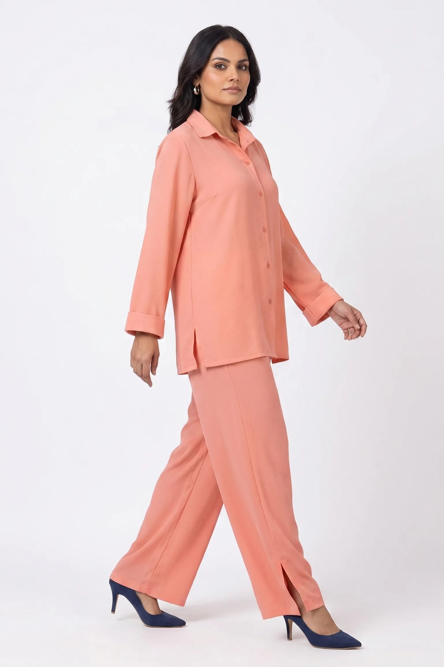 Woman wearing a peach suit with navy shoes on a white background