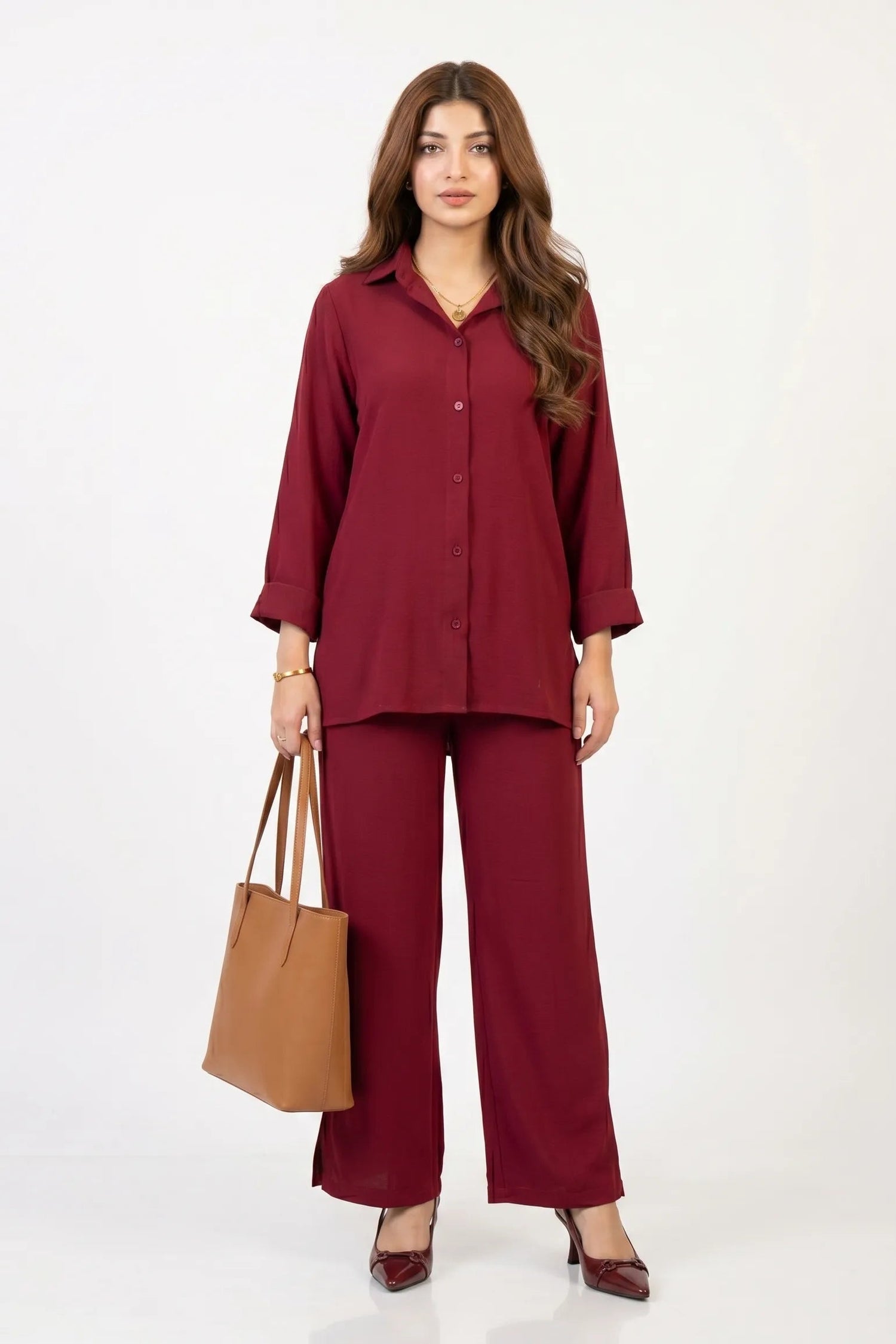 Woman wearing a maroon outfit with a brown handbag on a white background