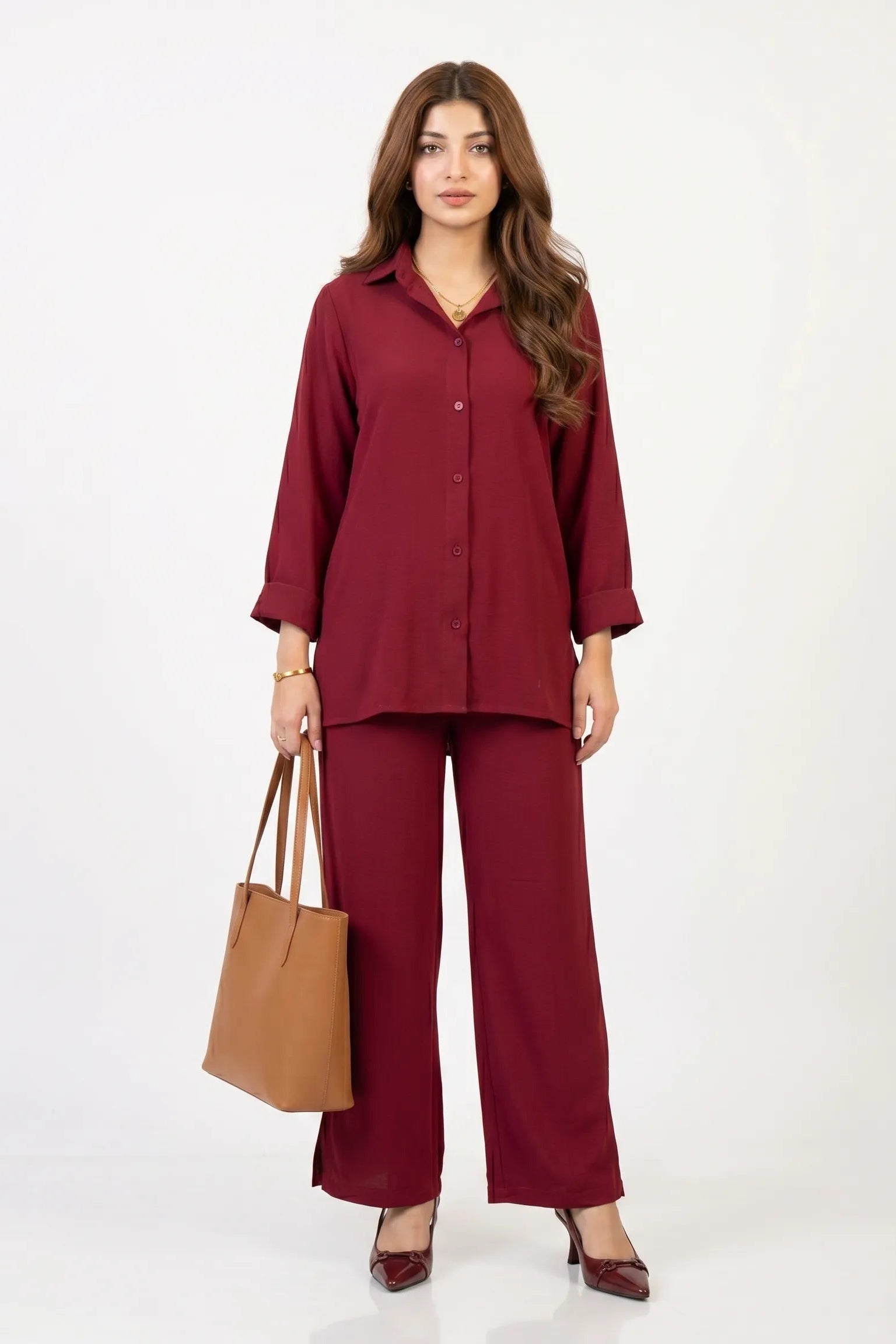 Woman wearing a maroon outfit with a brown handbag on a white background