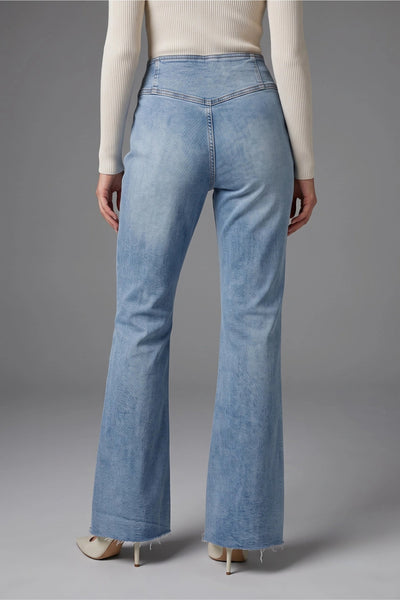 A person shown from the back wearing light-wash blue flare jeans, a cream ribbed long-sleeve top, and beige pointed-toe heels against a plain gray studio background.