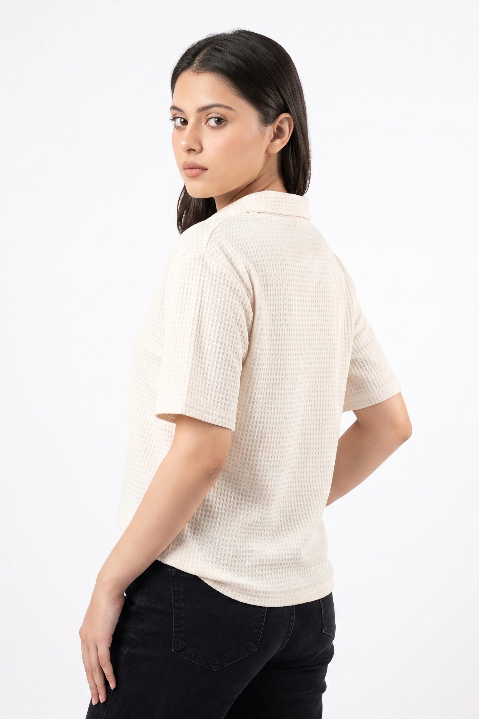 Back view of a model wearing an off-white waffle knit short sleeve shirt with drop shoulders.