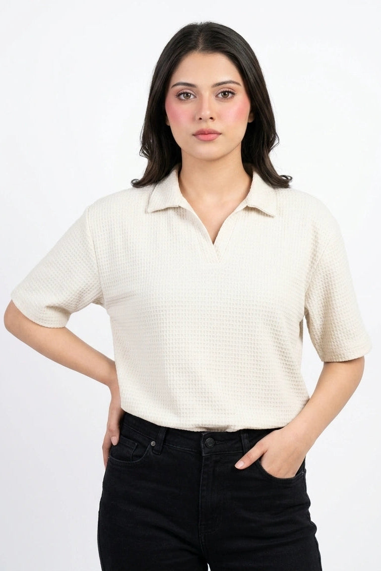 Close-up front view of a model wearing an off-white open neck waffle knit polo shirt.