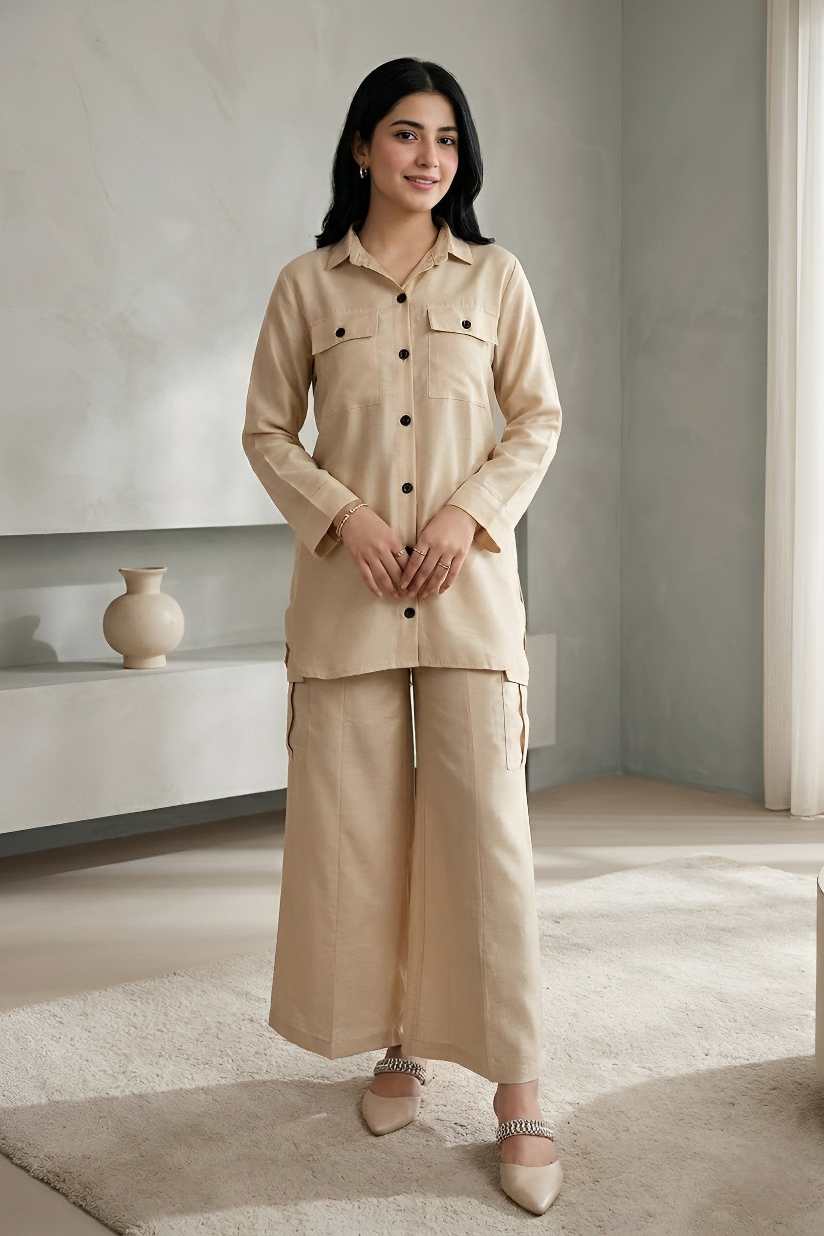 Woman wearing a beige co ord set standing in a minimalistic room 