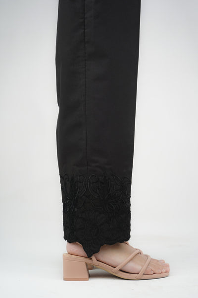 A pair of black embroidered cigarette pants on a model who is facing away from the camera.