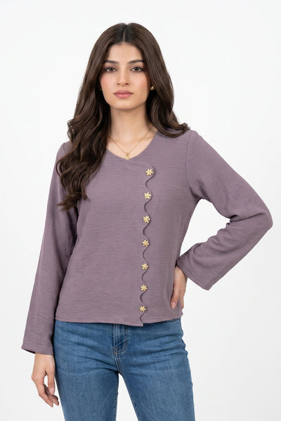 A woman modeling a dusty purple long-sleeve top with decorative gold star-shaped buttons down the front, paired with blue jeans, against a plain white background.