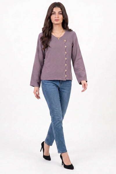A woman modeling a dusty purple long-sleeve top with gold buttons down the front, paired with blue jeans and black heels, against a plain white studio background.